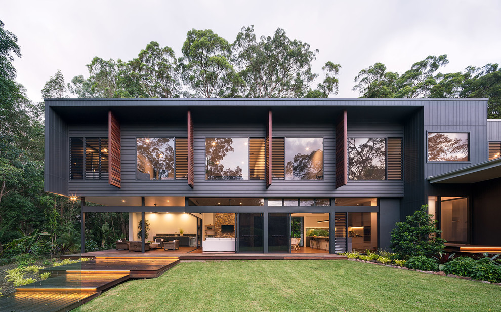 Стильный дизайн: двухэтажный, черный частный загородный дом среднего размера в современном стиле с облицовкой из ЦСП, плоской крышей и металлической крышей - последний тренд