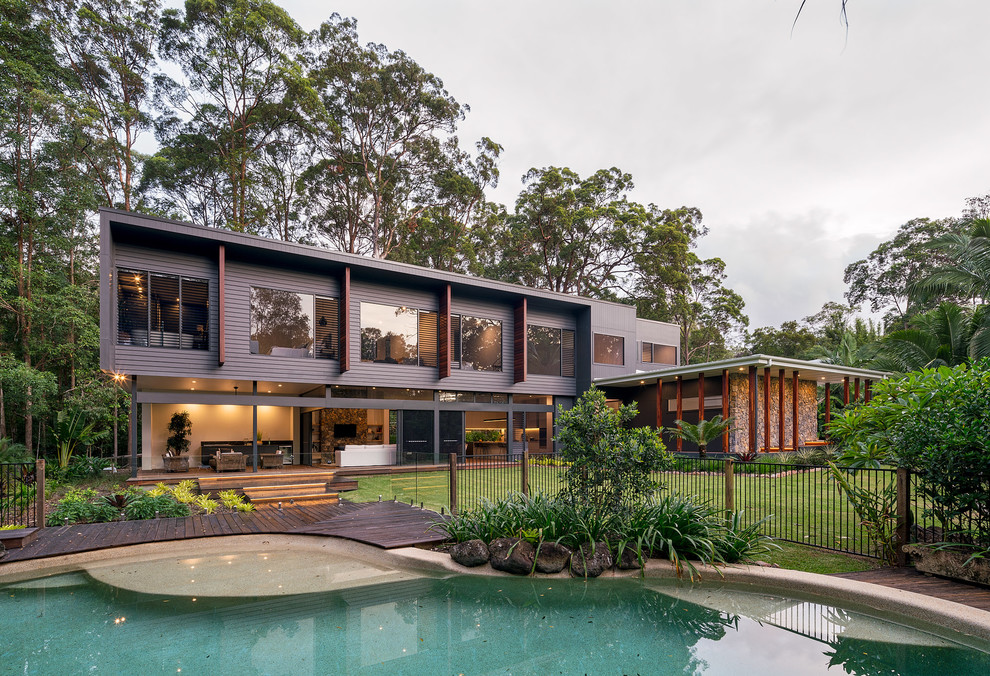 This is an example of a medium sized and black contemporary two floor detached house in Sunshine Coast with concrete fibreboard cladding, a flat roof and a metal roof.