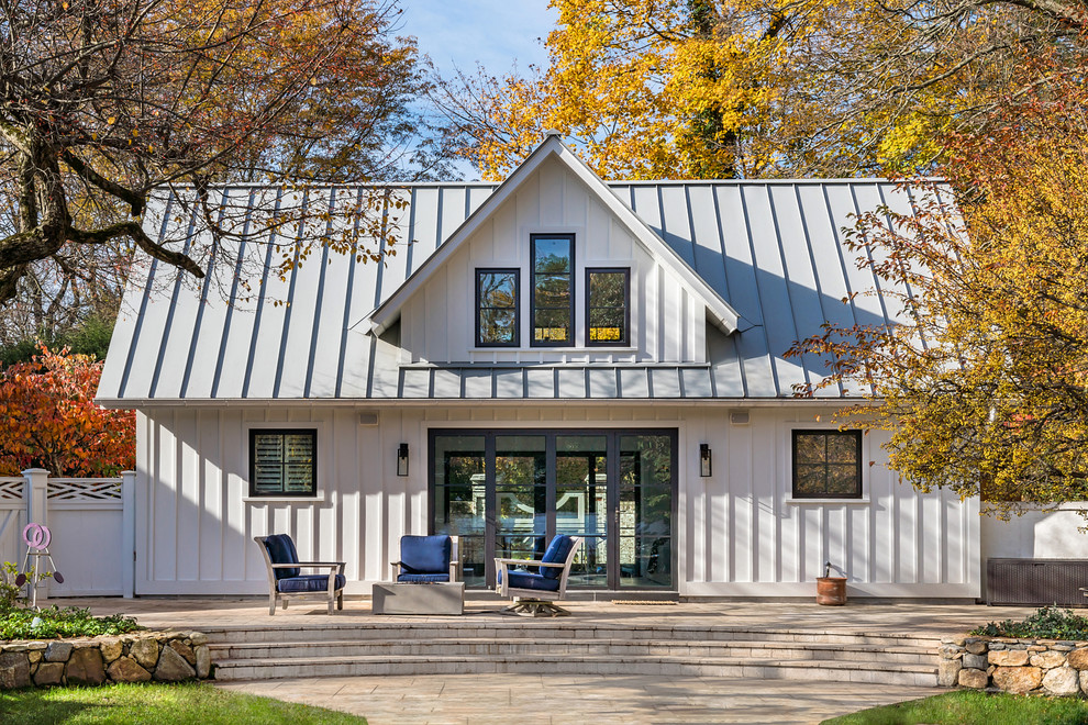 Modelo de fachada de casa blanca costera de dos plantas con tejado a dos aguas y tejado de metal