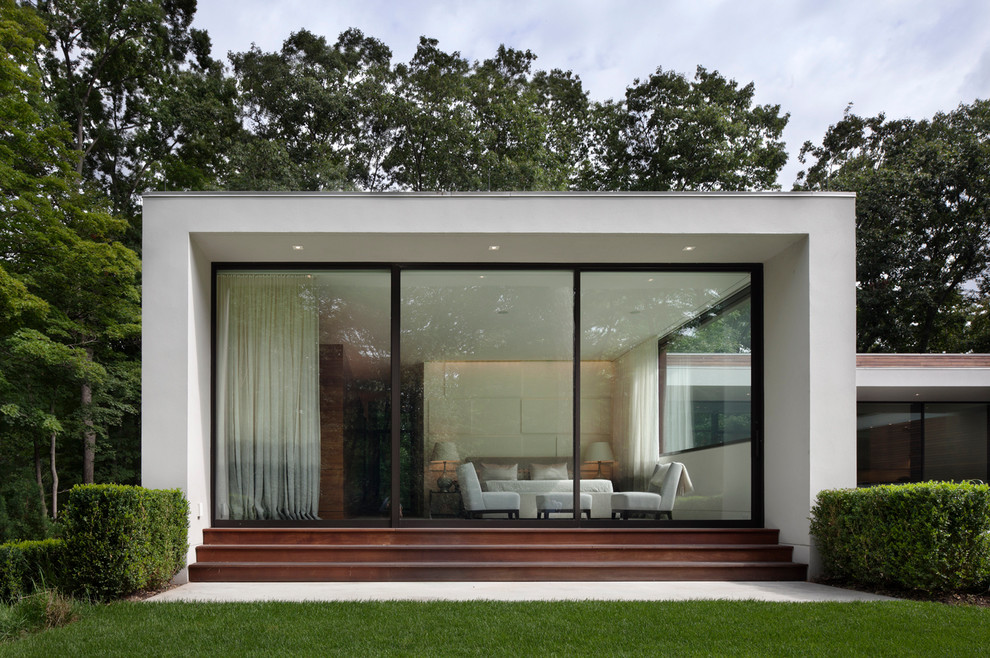 Photo of a white and large modern bungalow render house exterior in New York with a flat roof.