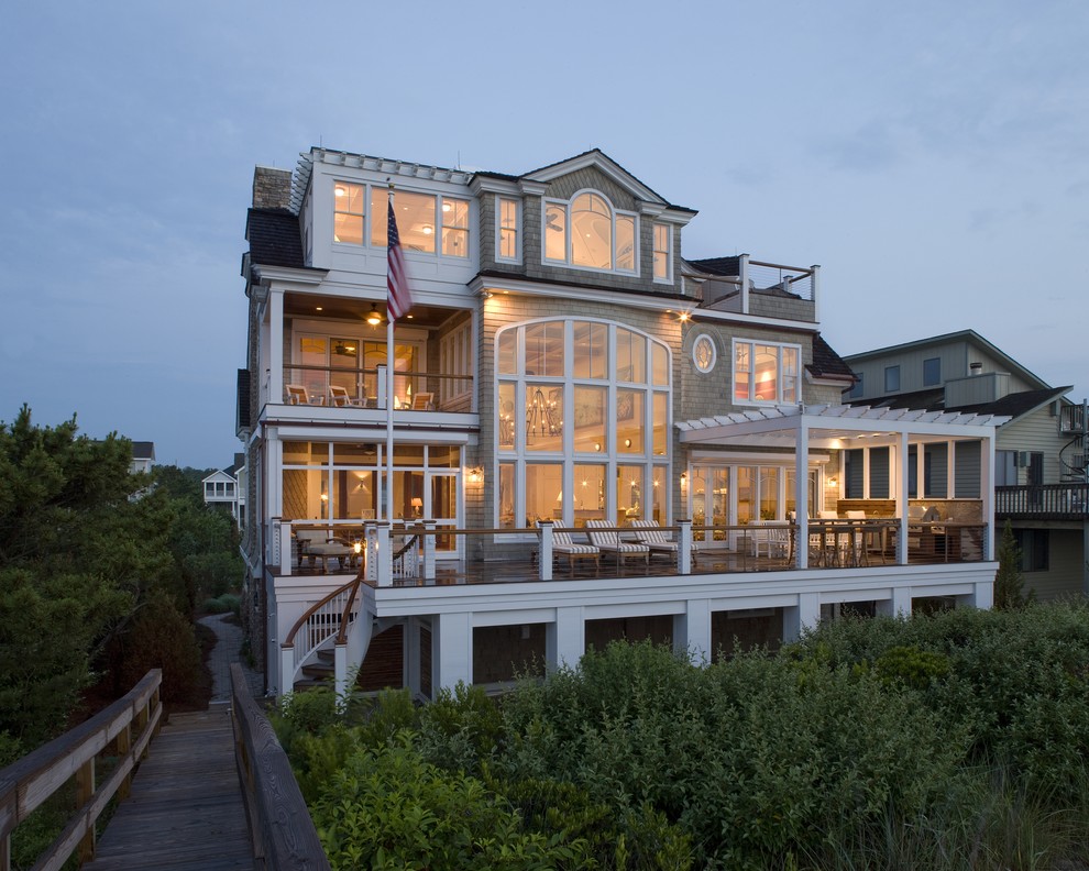 Aménagement d'une grande façade de maison marron bord de mer en bois à deux étages et plus avec un toit à deux pans.
