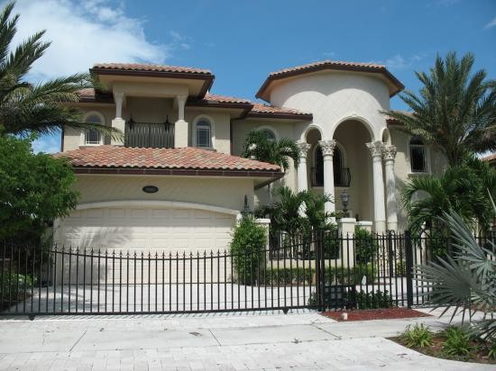 Inspiration for a large and beige mediterranean two floor concrete house exterior in Miami with a hip roof.