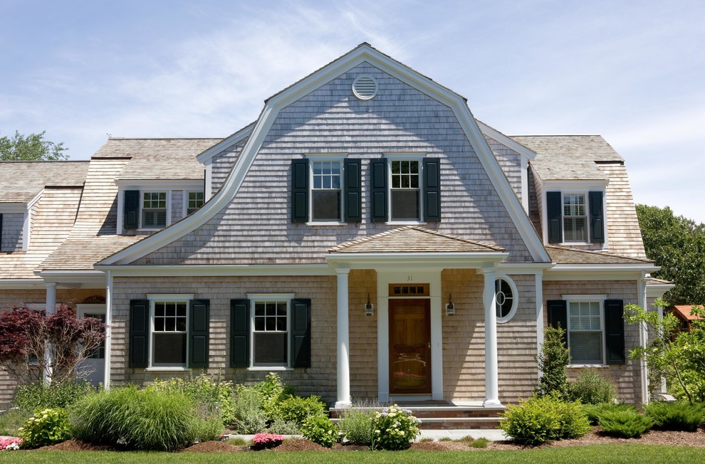 Photo of a beach style two floor house exterior in Boston with wood cladding and a mansard roof.