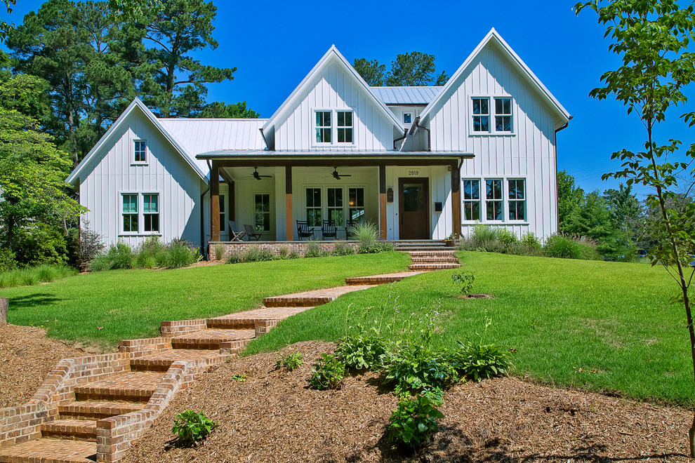 Modelo de fachada de casa blanca de estilo de casa de campo de tamaño medio de dos plantas con revestimiento de aglomerado de cemento, tejado a dos aguas y tejado de metal