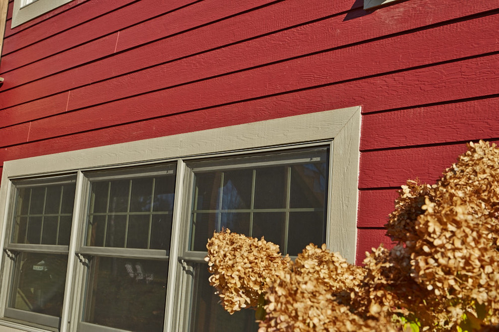Aménagement d'une grande façade de maison rouge classique en bois à un étage avec un toit à deux pans et un toit en shingle.