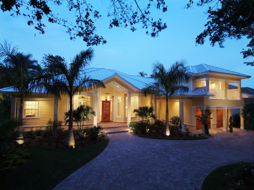 Immagine della villa grande tropicale a due piani con rivestimenti misti, tetto a padiglione e copertura in metallo o lamiera