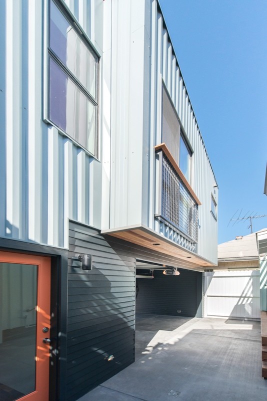 Foto della facciata di una casa piccola blu moderna a due piani con rivestimenti misti e tetto piano