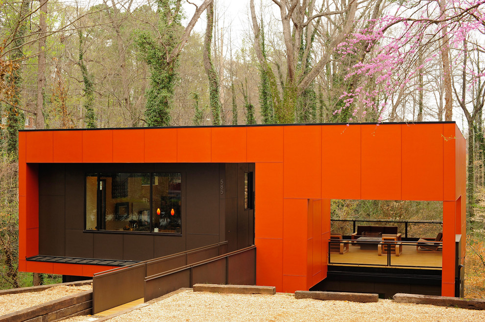Diseño de fachada de casa naranja y negra contemporánea grande de dos plantas con revestimiento de metal, tejado plano y tejado de metal