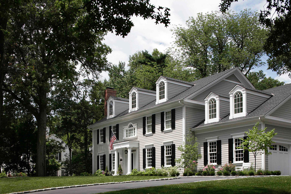 Mittelgroßes, Zweistöckiges Klassisches Einfamilienhaus mit grauer Fassadenfarbe, Satteldach, Schindeldach und Dachgaube in Kansas City
