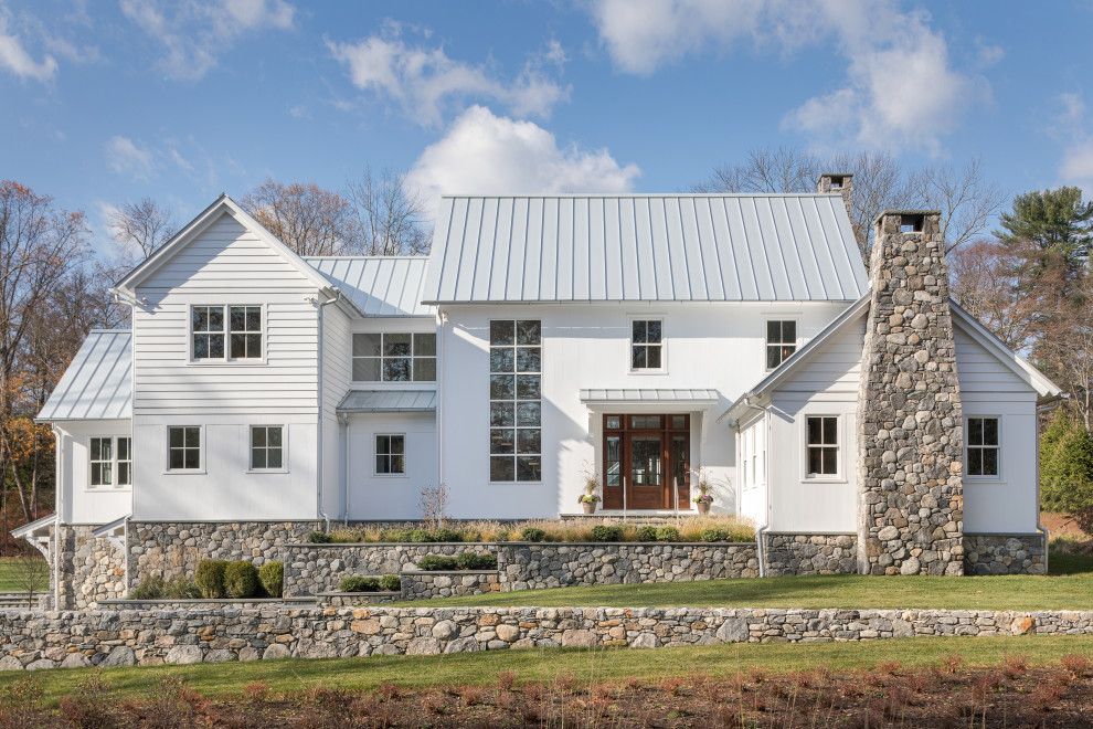 Immagine della villa grande bianca country a due piani con rivestimenti misti, tetto a capanna e copertura in metallo o lamiera