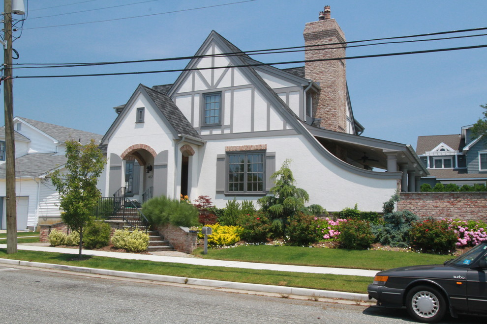 Large and white bohemian two floor render house exterior in Philadelphia with a pitched roof.