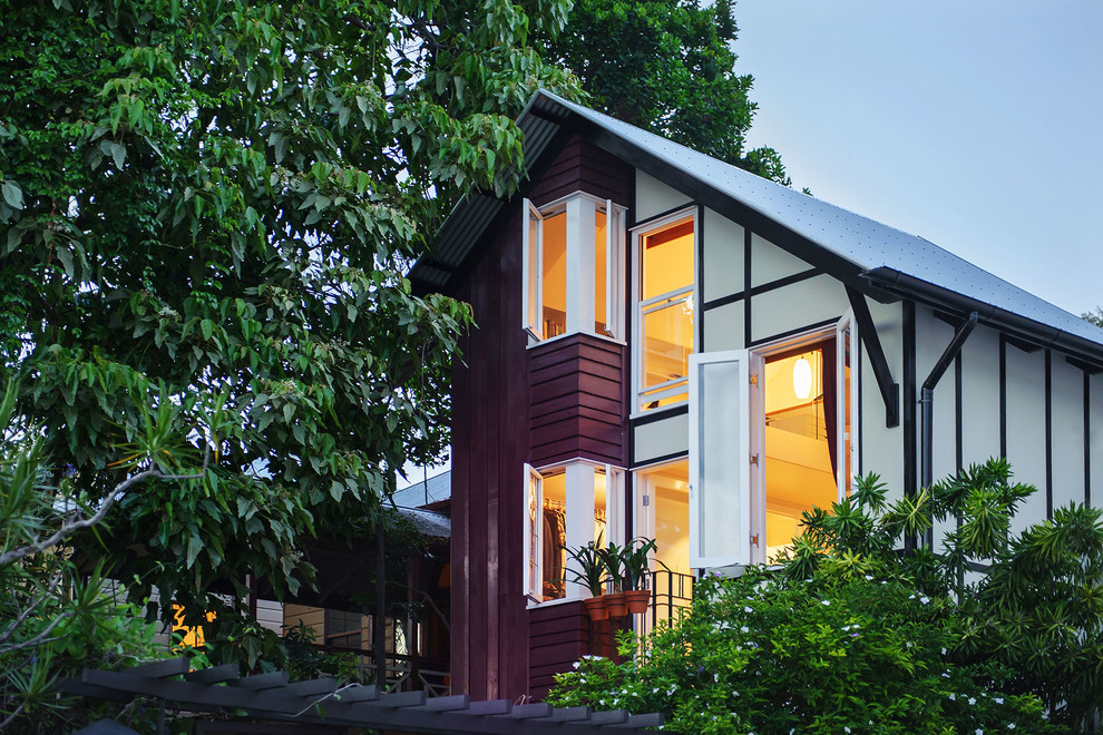 Small and multi-coloured contemporary detached house in Brisbane with three floors, a half-hip roof, a metal roof and wood cladding.