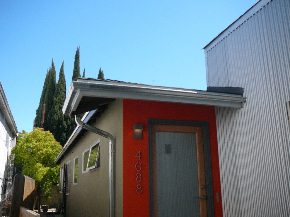 Foto della facciata di una casa piccola grigia industriale a un piano con rivestimento in metallo e tetto a capanna