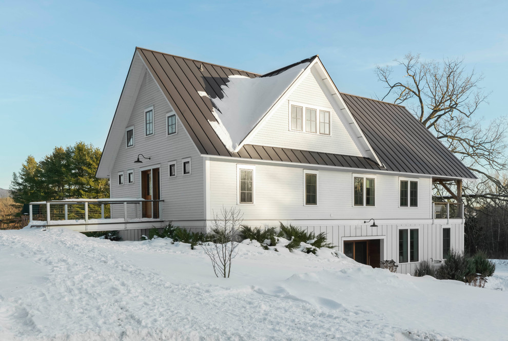 На фото: трехэтажный, белый частный загородный дом в стиле кантри с металлической крышей и двускатной крышей с
