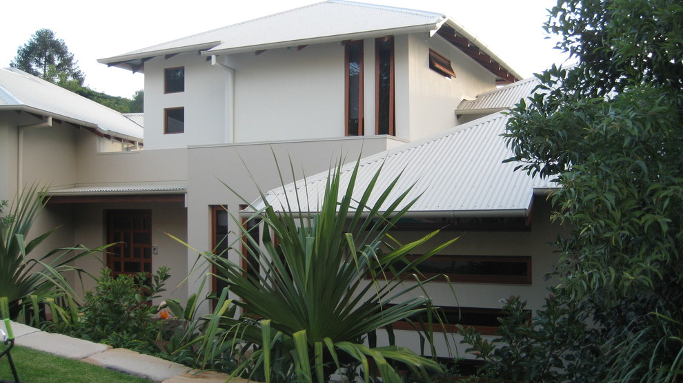 Large and beige contemporary two floor detached house in Brisbane with concrete fibreboard cladding, a hip roof and a metal roof.
