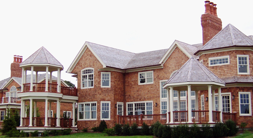 Cette image montre une grande façade de maison marron traditionnelle en bois à un étage avec un toit à deux pans.