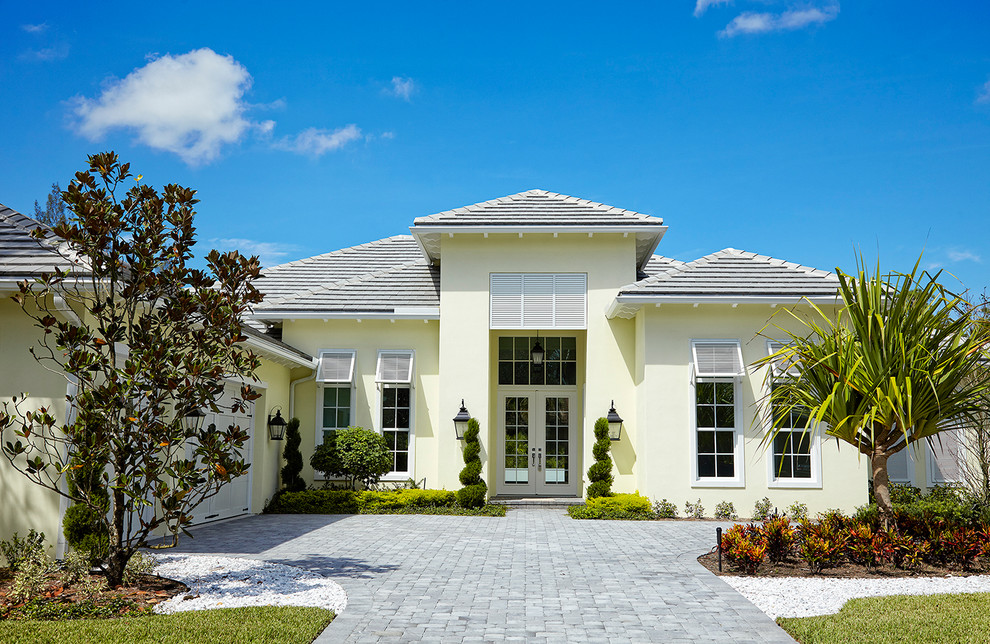 マイアミにある高級なトロピカルスタイルのおしゃれな家の外観 (漆喰サイディング、黄色い外壁) の写真