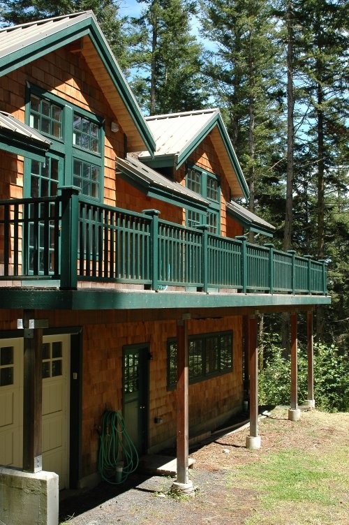 На фото: маленький, двухэтажный, деревянный, коричневый частный загородный дом в стиле рустика с двускатной крышей и металлической крышей для на участке и в саду