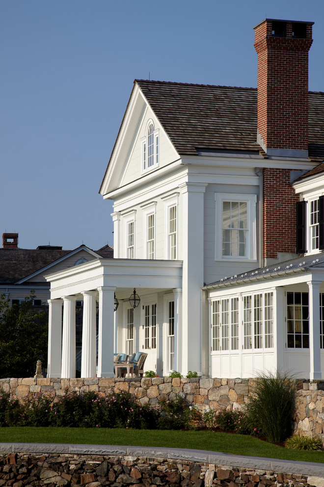 Imagen de fachada blanca clásica grande de dos plantas con revestimiento de madera y tejado a dos aguas