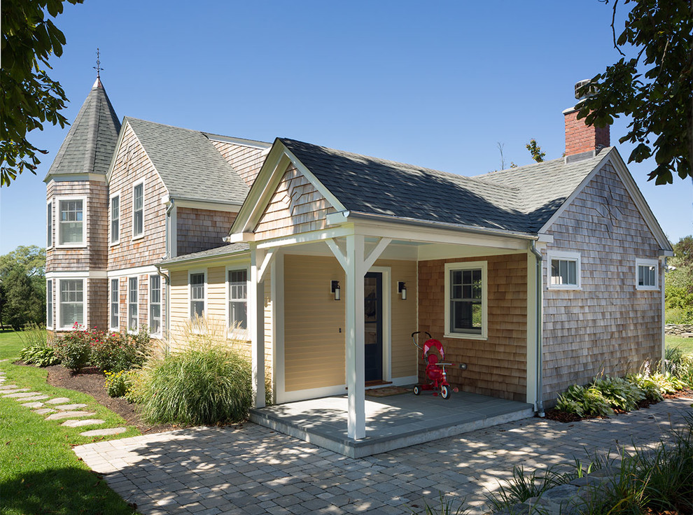 Idée de décoration pour une grande façade de maison beige champêtre en bois à un étage avec un toit à quatre pans et un toit en shingle.