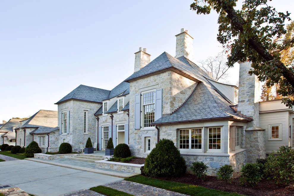 Example of a mid-sized classic gray two-story stone house exterior design in Charlotte with a hip roof and a shingle roof