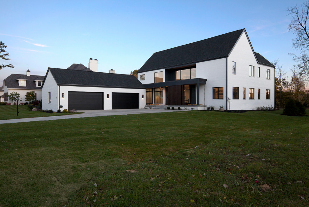 Imagen de fachada de casa blanca grande de dos plantas con revestimiento de ladrillo, tejado a dos aguas y tejado de teja de madera