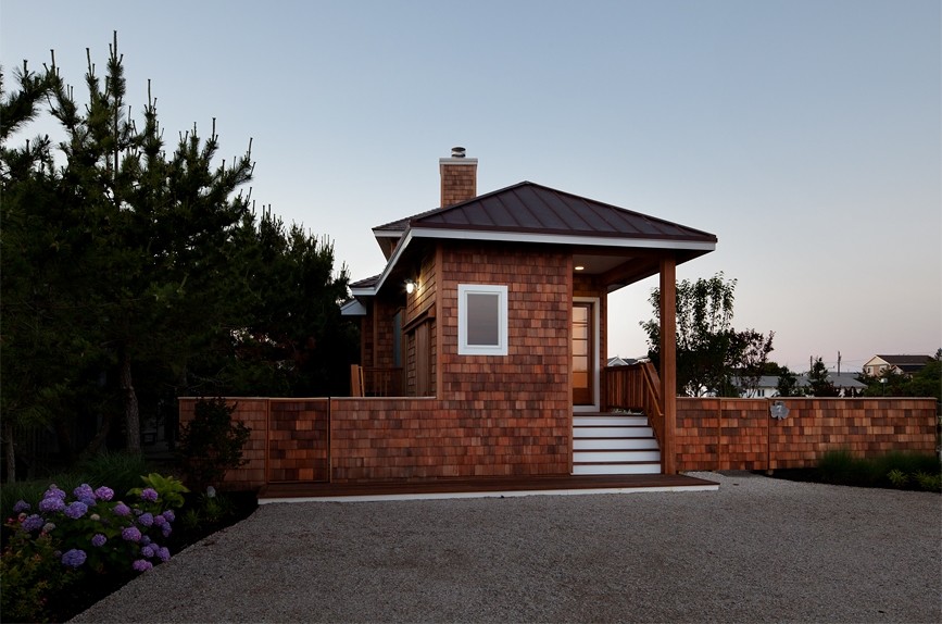 На фото: маленький, двухэтажный, деревянный, коричневый частный загородный дом в морском стиле с вальмовой крышей и металлической крышей для на участке и в саду