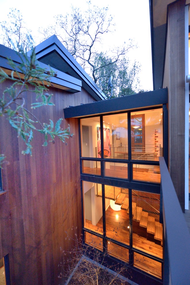 Idées déco pour une grande façade de maison marron moderne en bois à un étage avec un toit plat, un toit en métal et un toit gris.