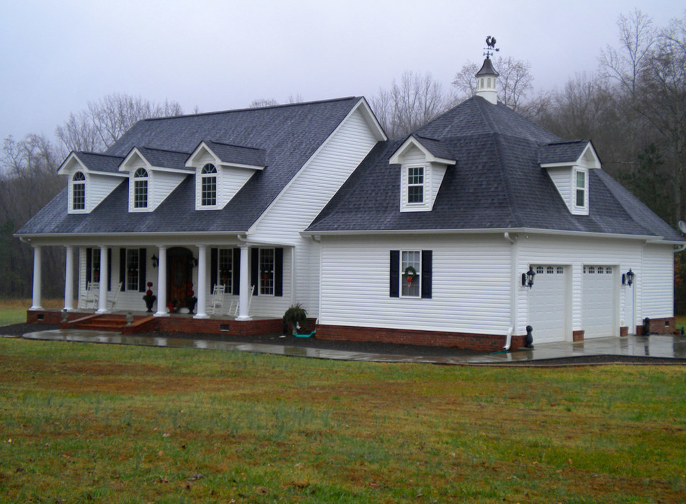 Пример оригинального дизайна: большой, двухэтажный, белый частный загородный дом в стиле кантри с облицовкой из винила, двускатной крышей и крышей из гибкой черепицы