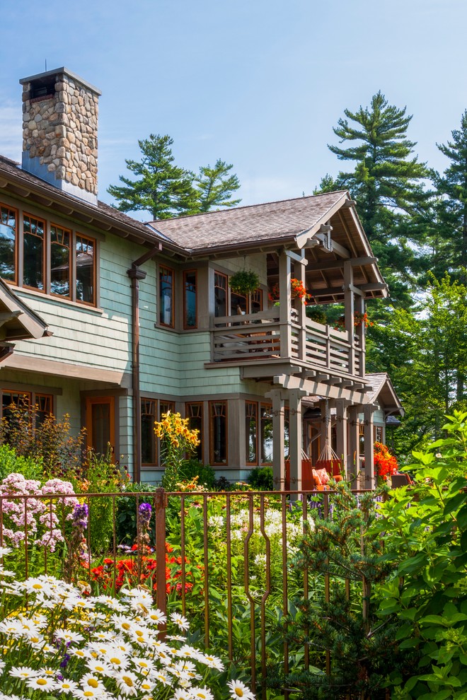 Ejemplo de fachada de casa verde de estilo americano de tamaño medio de dos plantas con revestimiento de madera, tejado a dos aguas y tejado de teja de madera