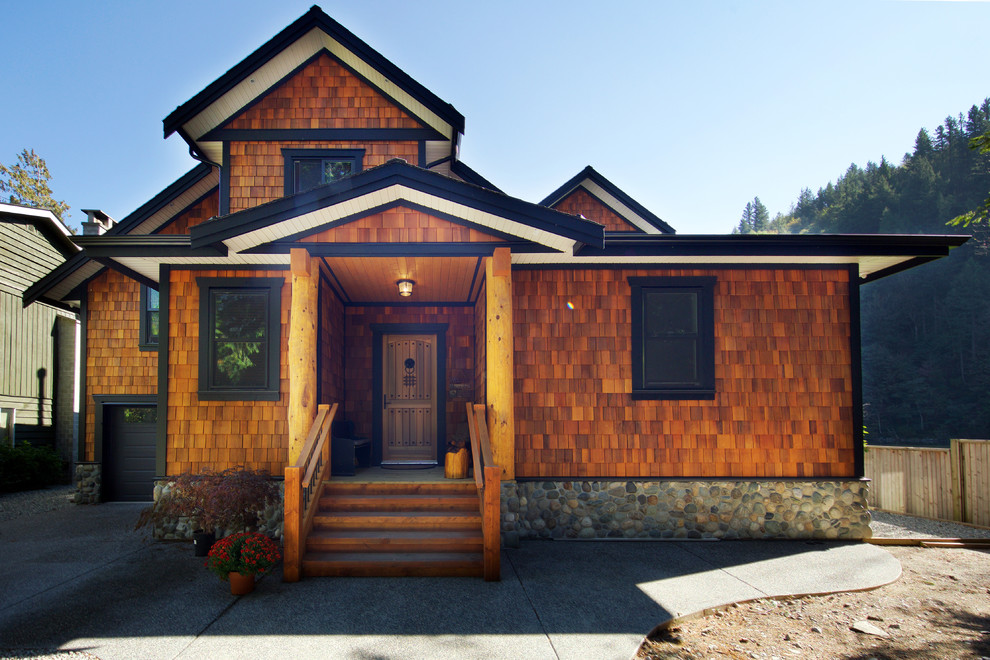 Esempio della facciata di una casa marrone rustica a due piani di medie dimensioni con rivestimento in legno e falda a timpano