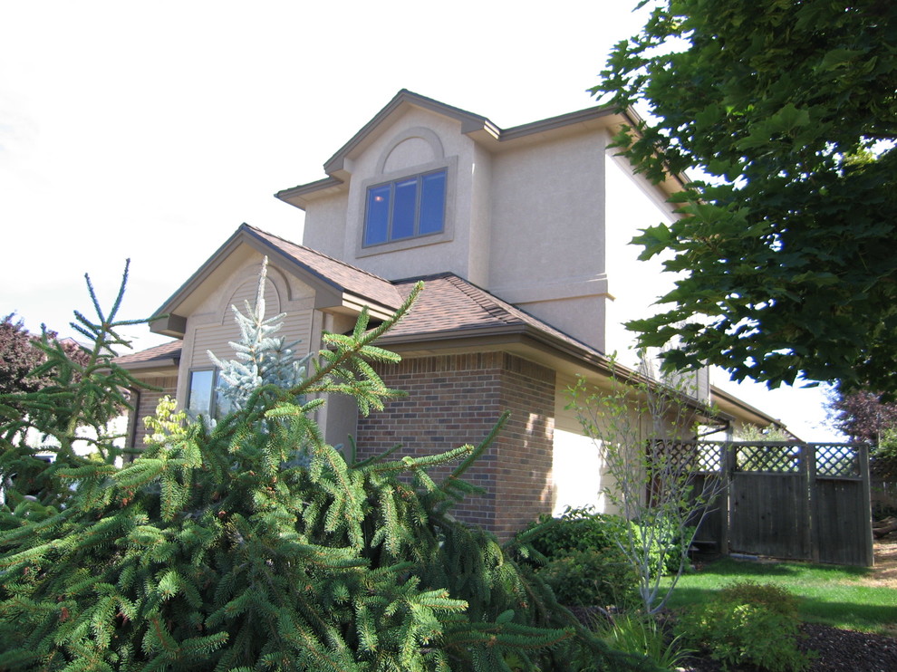 На фото: двухэтажный, бежевый дом среднего размера с облицовкой из цементной штукатурки