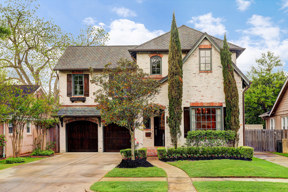 Inspiration for a timeless beige two-story brick house exterior remodel in Houston with a hip roof and a shingle roof