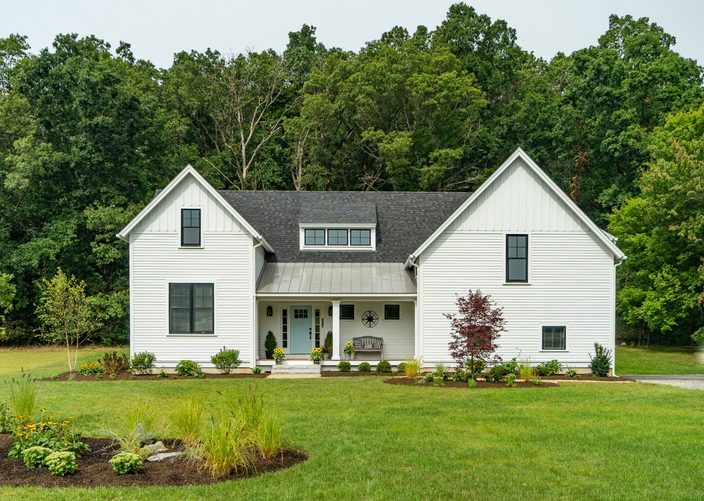 Immagine della villa grande bianca country a due piani con tetto a capanna e copertura a scandole