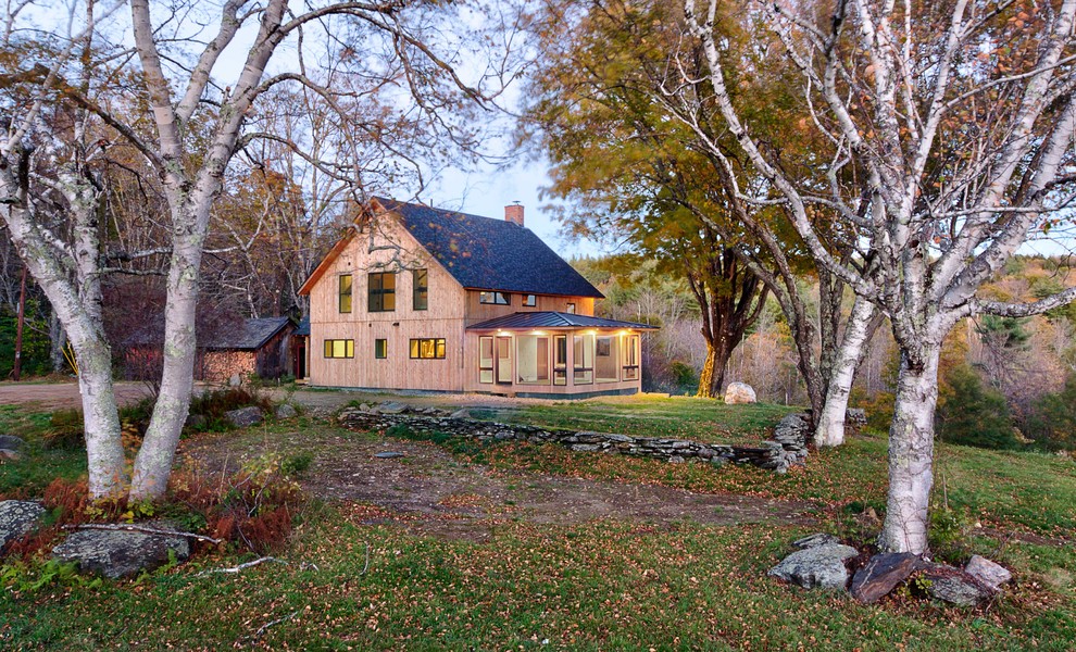 Foto della villa country a due piani con rivestimento in legno, tetto a capanna e copertura a scandole