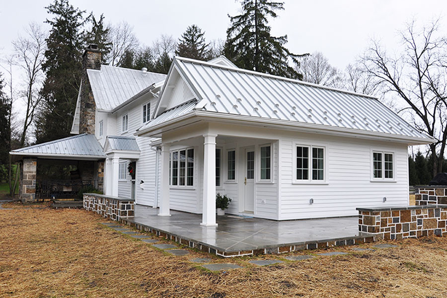 Cette image montre une façade de maison blanche rustique de taille moyenne et à un étage avec un revêtement en vinyle et un toit à deux pans.