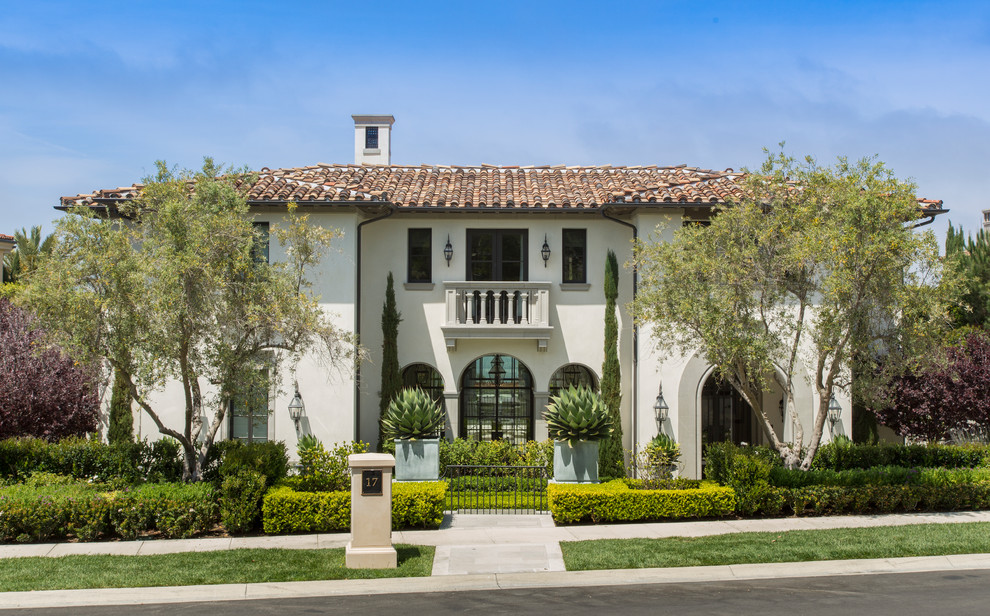 Inspiration for a mediterranean white two-story stucco house exterior remodel in Orange County with a hip roof and a tile roof