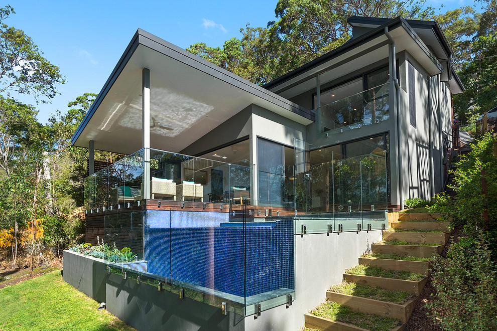 Réalisation d'une façade de maison grise minimaliste en béton de taille moyenne et à un étage avec un toit plat.