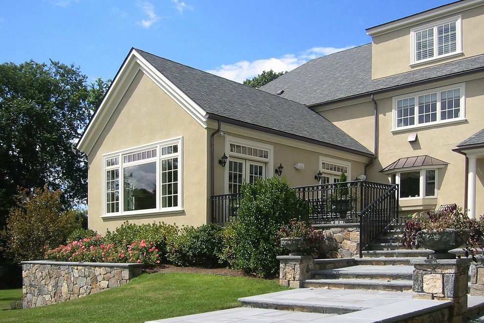 Example of a huge classic beige three-story stucco exterior home design in Boston with a shingle roof