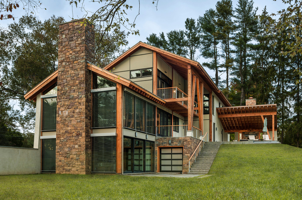 Diseño de fachada de casa beige rural grande de dos plantas con tejado a dos aguas, revestimiento de estuco y tejado de metal