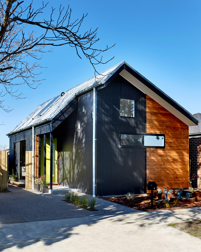 Cette photo montre une façade de maison noire tendance en bois de plain-pied avec un toit à deux pans.