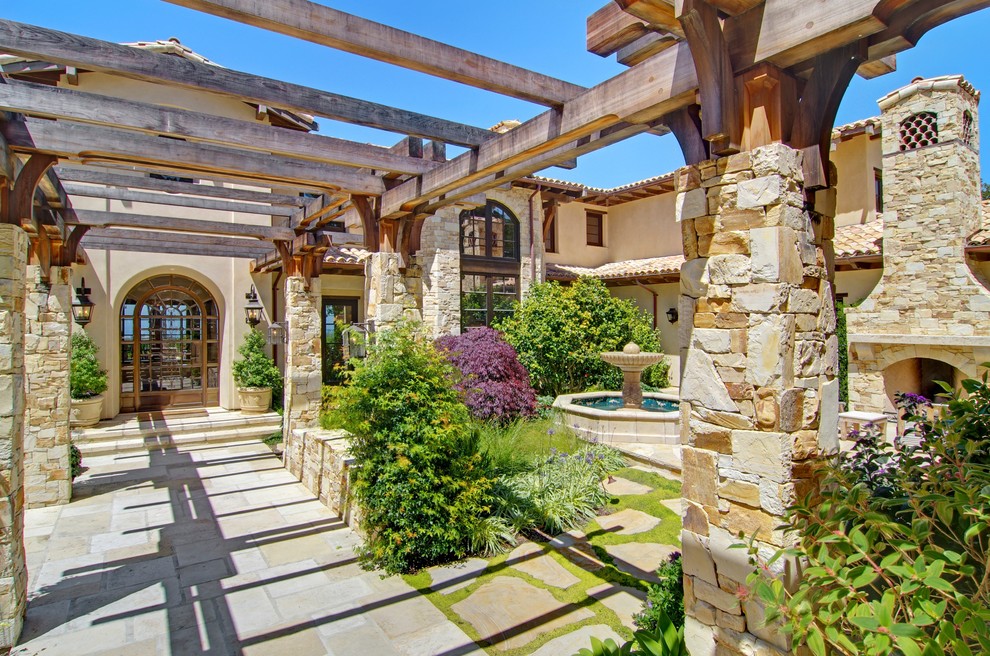 Idée de décoration pour une grande façade de maison beige méditerranéenne en pierre à un étage.