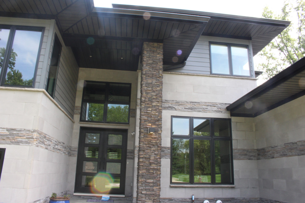 Diseño de fachada de casa gris minimalista grande de dos plantas con revestimiento de aglomerado de cemento, tejado a cuatro aguas y tejado de teja de madera