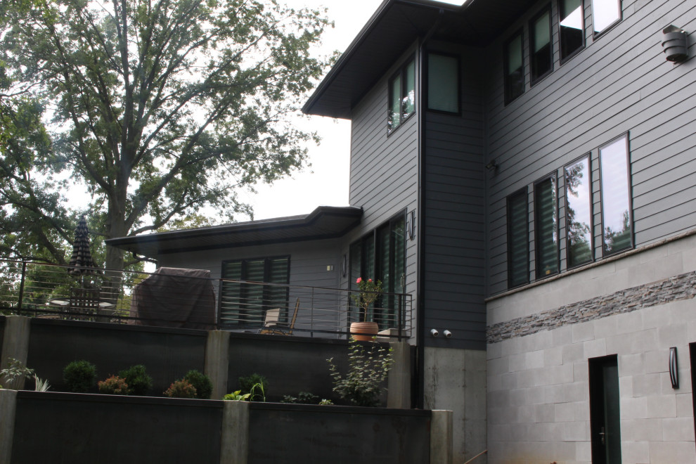 Cette photo montre une grande façade de maison grise moderne en panneau de béton fibré à un étage avec un toit à quatre pans et un toit en shingle.