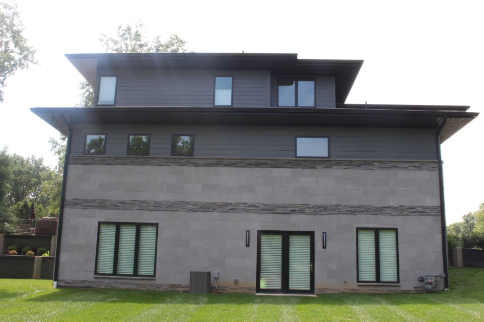 Ejemplo de fachada de casa gris minimalista grande de dos plantas con revestimiento de aglomerado de cemento, tejado a cuatro aguas y tejado de teja de madera