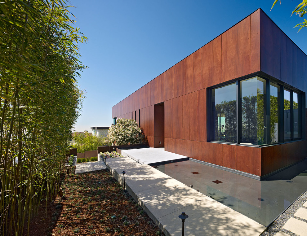 На фото: большой, коричневый дом в современном стиле с разными уровнями, облицовкой из бетона и плоской крышей