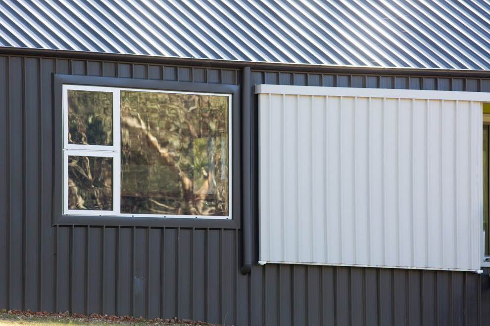 Immagine della facciata di una casa grigia industriale a un piano con rivestimento in metallo