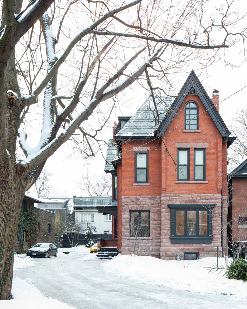 Red traditional brick house exterior in Toronto with three floors.