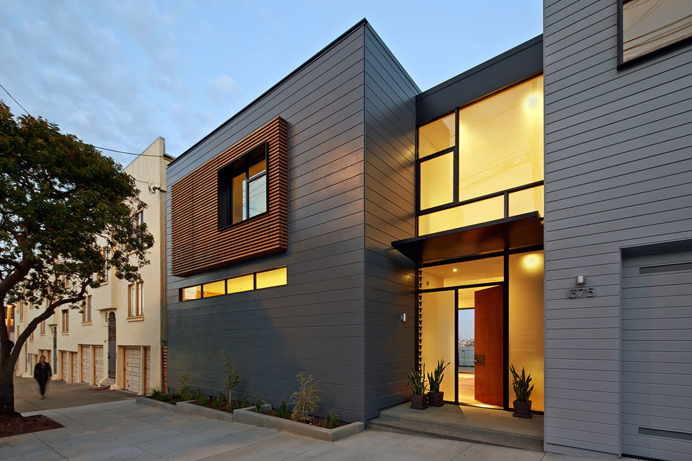 Cette photo montre une façade de maison grise tendance à un étage avec un toit plat.
