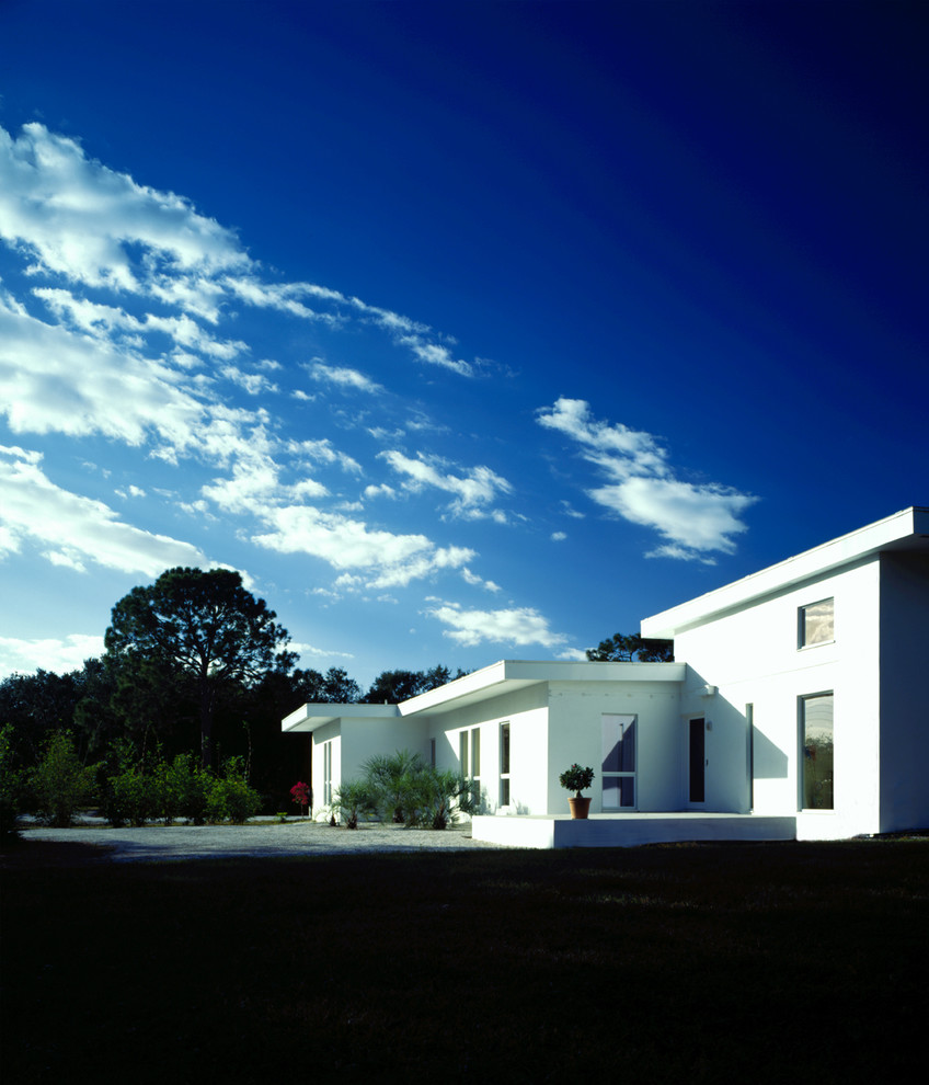 Foto på ett stort funkis vitt hus, med allt i ett plan, stuckatur och platt tak
